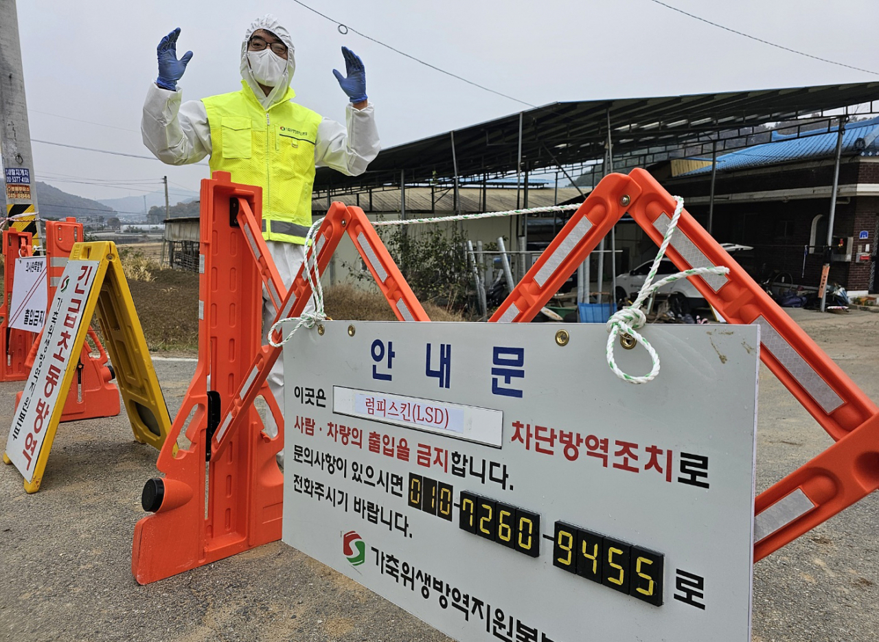 A quarantine official blocks off access to a farm in Hoengseong, Gangwon Province, on Thursday, after an outbreak of lumpy skin disease infected cattle there. (Yonhap)