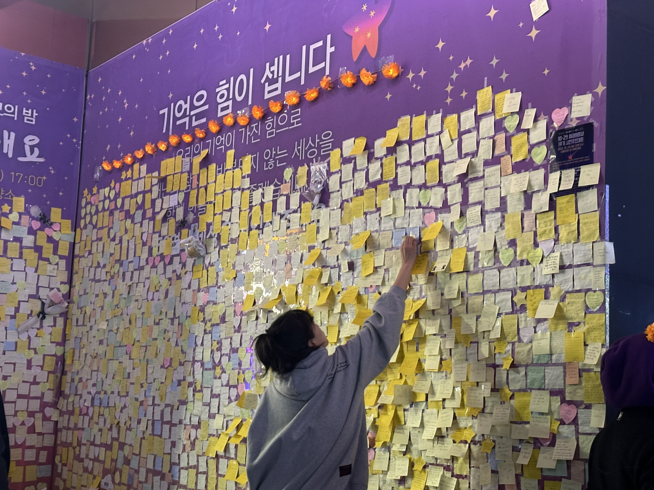 A visitor plasters their condolence message on the memorial wall set up to remember the victims of the Itaewon crowd crush on Saturday. (Lee Jung-joo/The Korea Herald)
