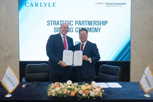 Korea Investment & Securities CEO Jung Il-moon (right) and Harvey Schwartz, CEO of Carlyle Group, pose for photos at a signing ceremony held at the Korean brokerage house’s headquarters in Yeouido, western Seoul, Friday. (Korea Investment & Securities)