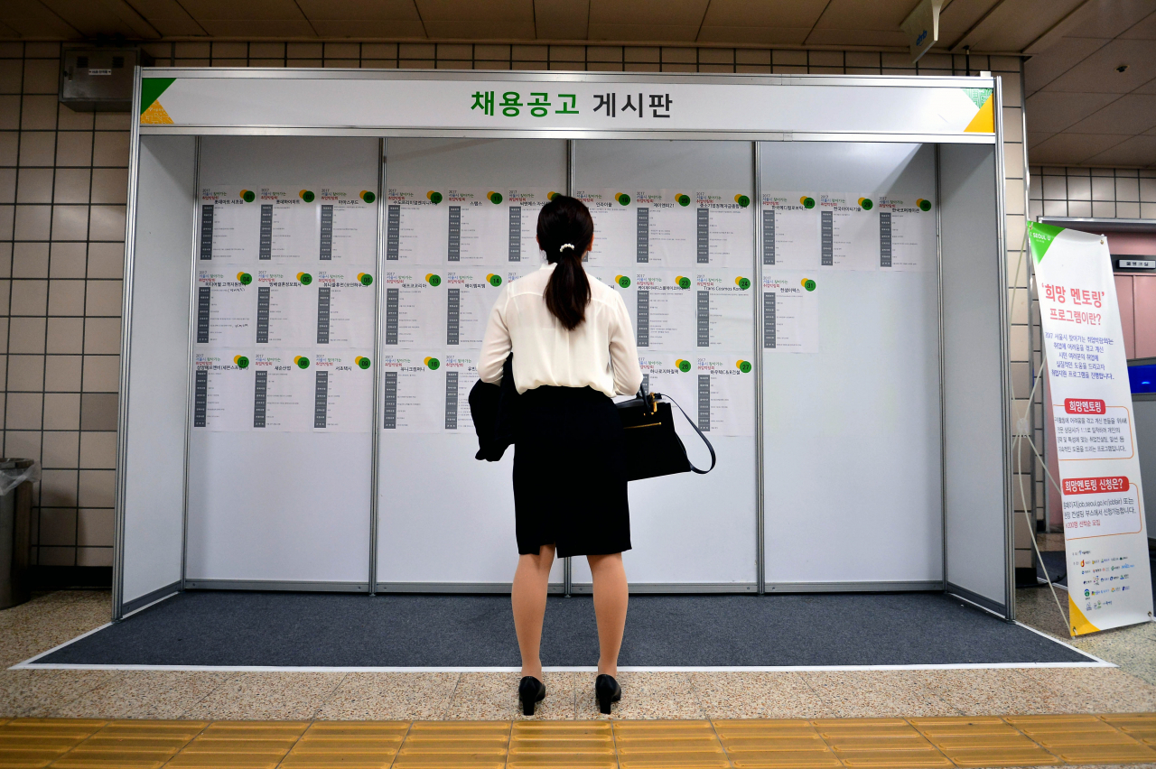 A young woman looks at job offers posted on a bulletin board in Cheongdam Station in Seoul in 2017. (Newsis)