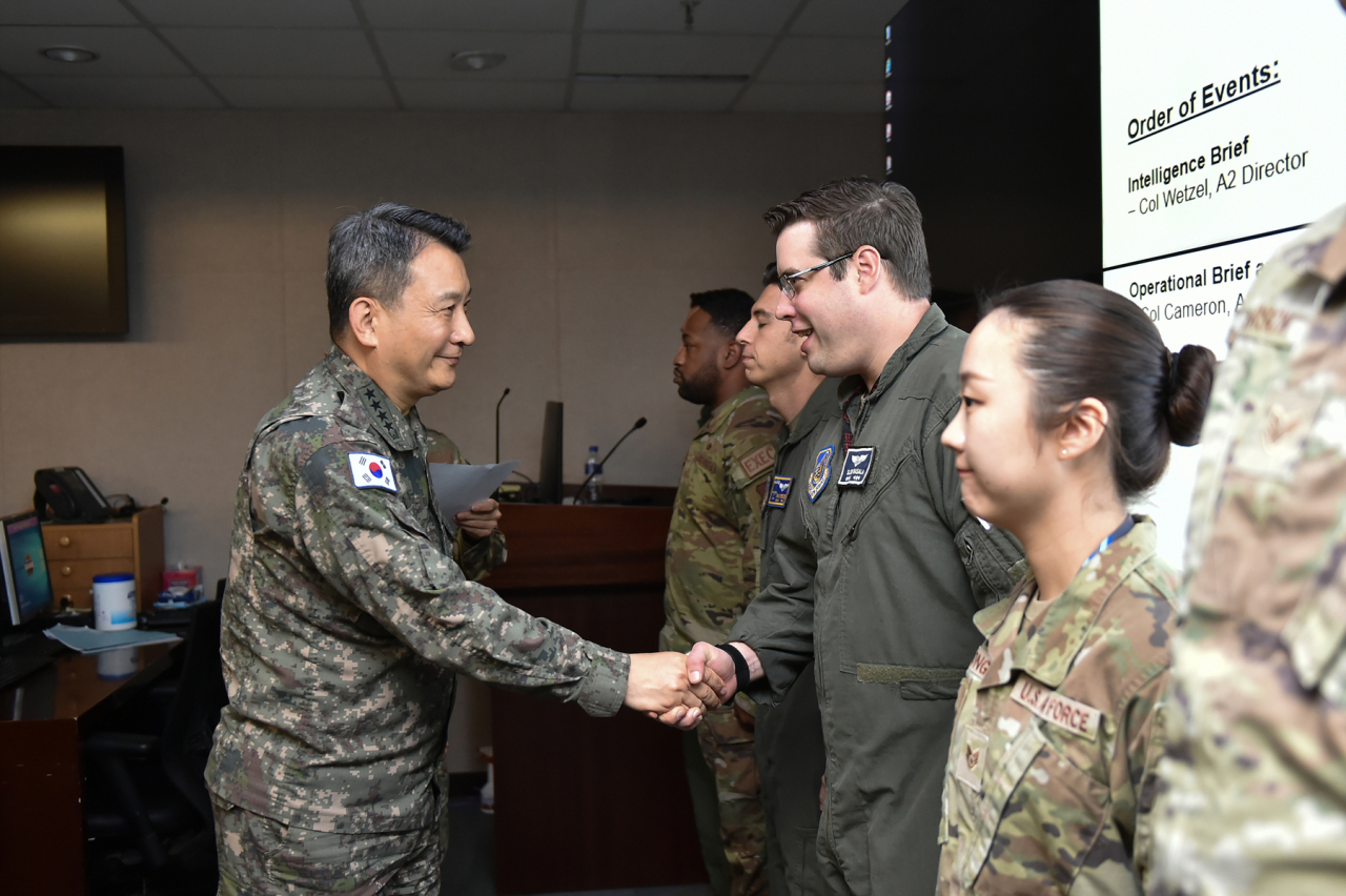 South Korea's Joint Chiefs of Staff Chairman Gen. Kim Seung-kyum (left) shakes hands with a US service member at the Korea Air and Space Operations Center at Osan Air Base in Pyeongtaek, 60 kilometers south of Seoul on Thursday in this picture provided by his office. (Yonhap)
