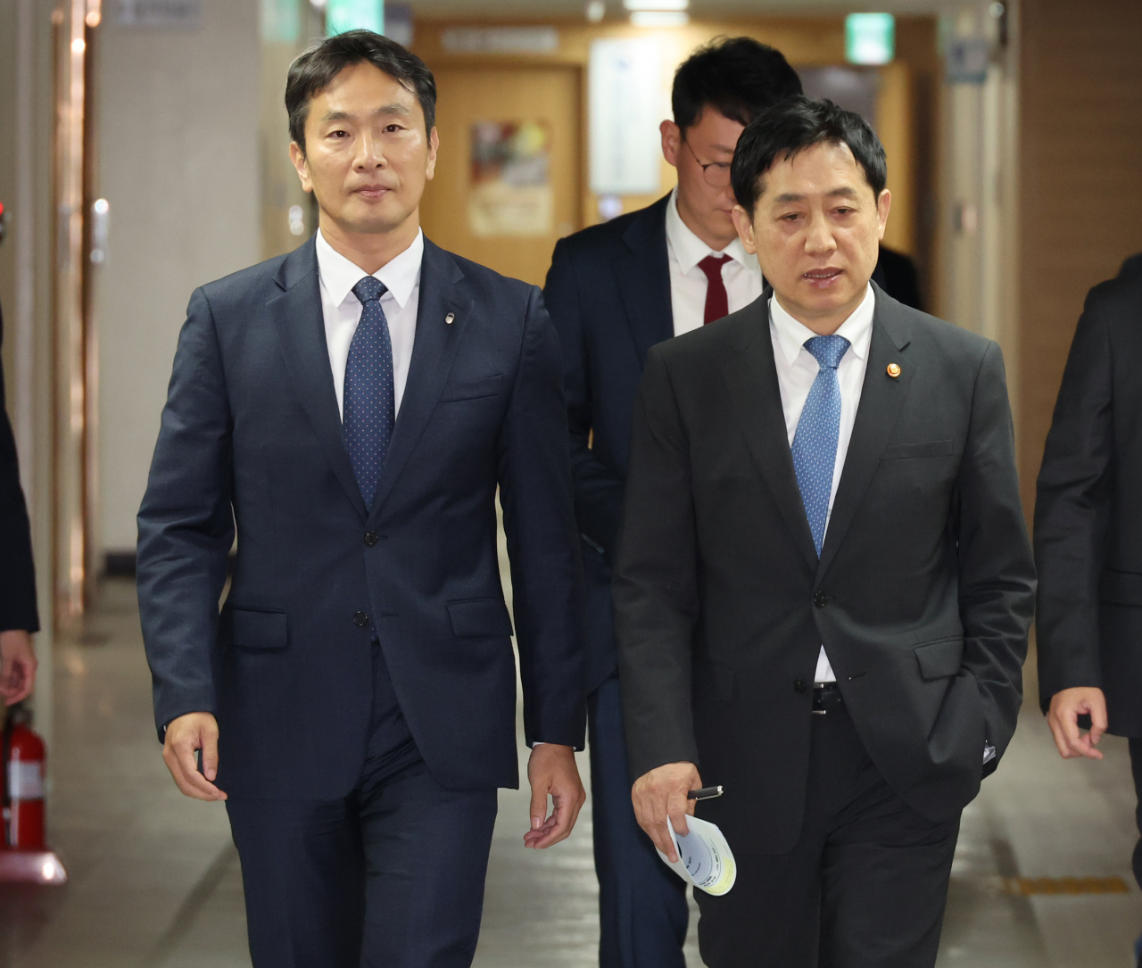 Financial Services Commission Chairman Kim Joo-hyun (right) and Financial Supervisory Service Governor Lee Bok-hyun walk toward a press briefing room at the government complex in Seoul on Sunday. (Yonhap)