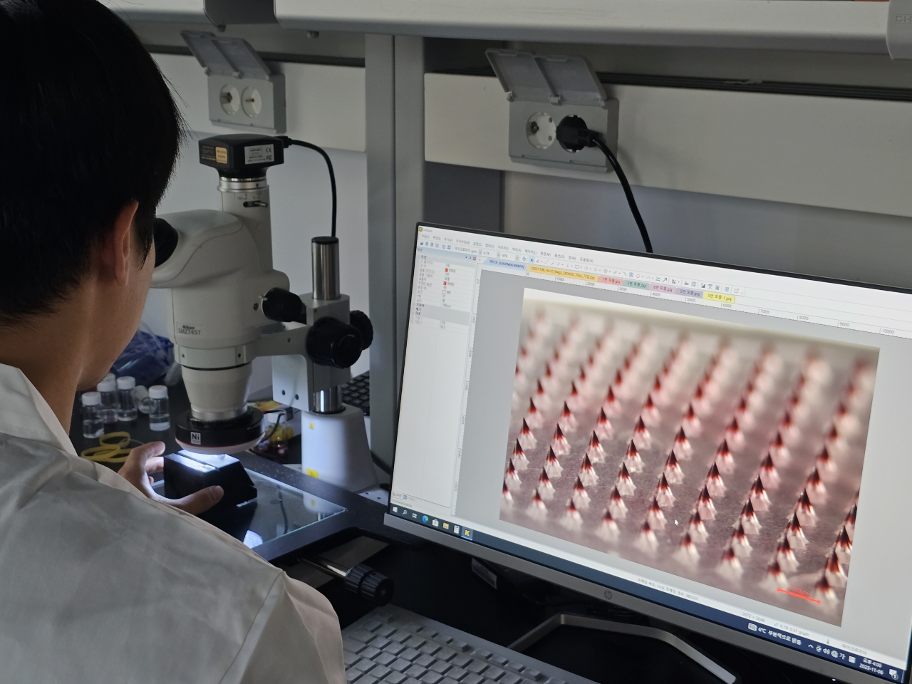 A Daewoong Pharmaceutical researcher shows the company's microneedle platform through a microscope. (Daewoong Pharmaceutical)