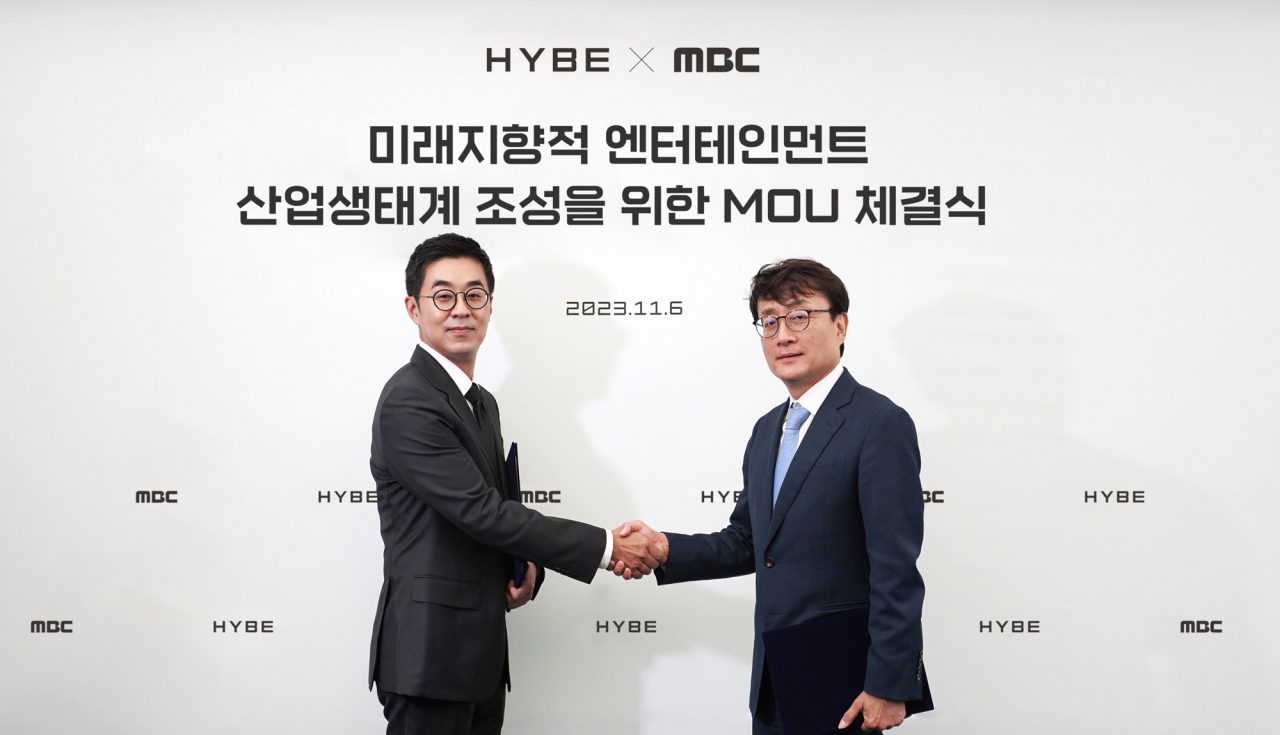 Hybe CEO Park Ji-won (left) and MBC President Ahn Hyung-joon pose for a photo after signing a memorandum of understanding at Hybe’s headquarters in Yongsan-gu, central Seoul, on Monday. (Hybe)