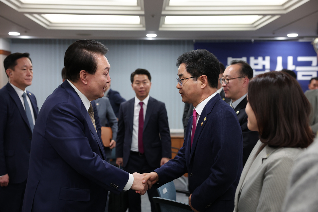 President Yoon Suk Yeol shake hands with Kim Chang-ki, the chief of the National Tax Service, during a meeting on illegal private financing, Thursday. (Yonhap)