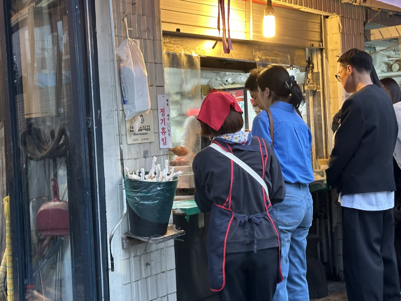 Passersby line up in front of a snack store that sells items including 