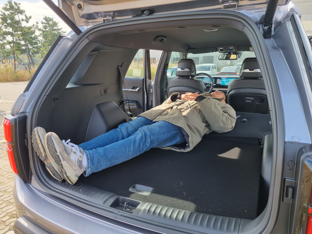 The Korea Herald reporter lies down in the back of the Torres EVX with the back seats fully folded during a test drive in Incheon on Wednesday. (Kan Hyeong-woo/The Korea Herald)