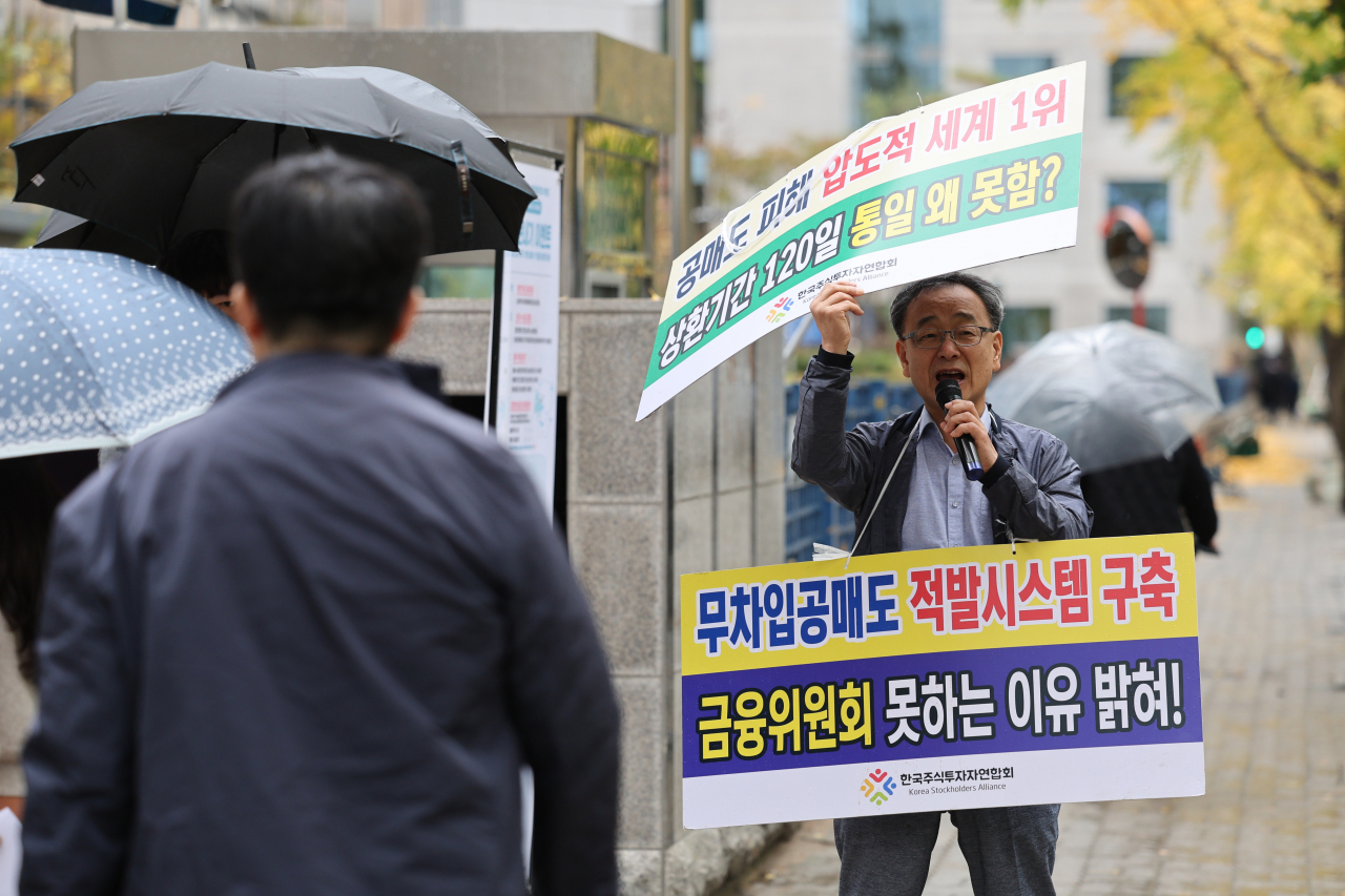 Jung Eui-jung (right), who heads an advocacy group representing retail investors, stages a protest calling on the financial authorities to tackle deficiencies in the system against short sellers on Monday in front of the Korea Exchange office in Yeouido business district in Seoul. (Yonhap)