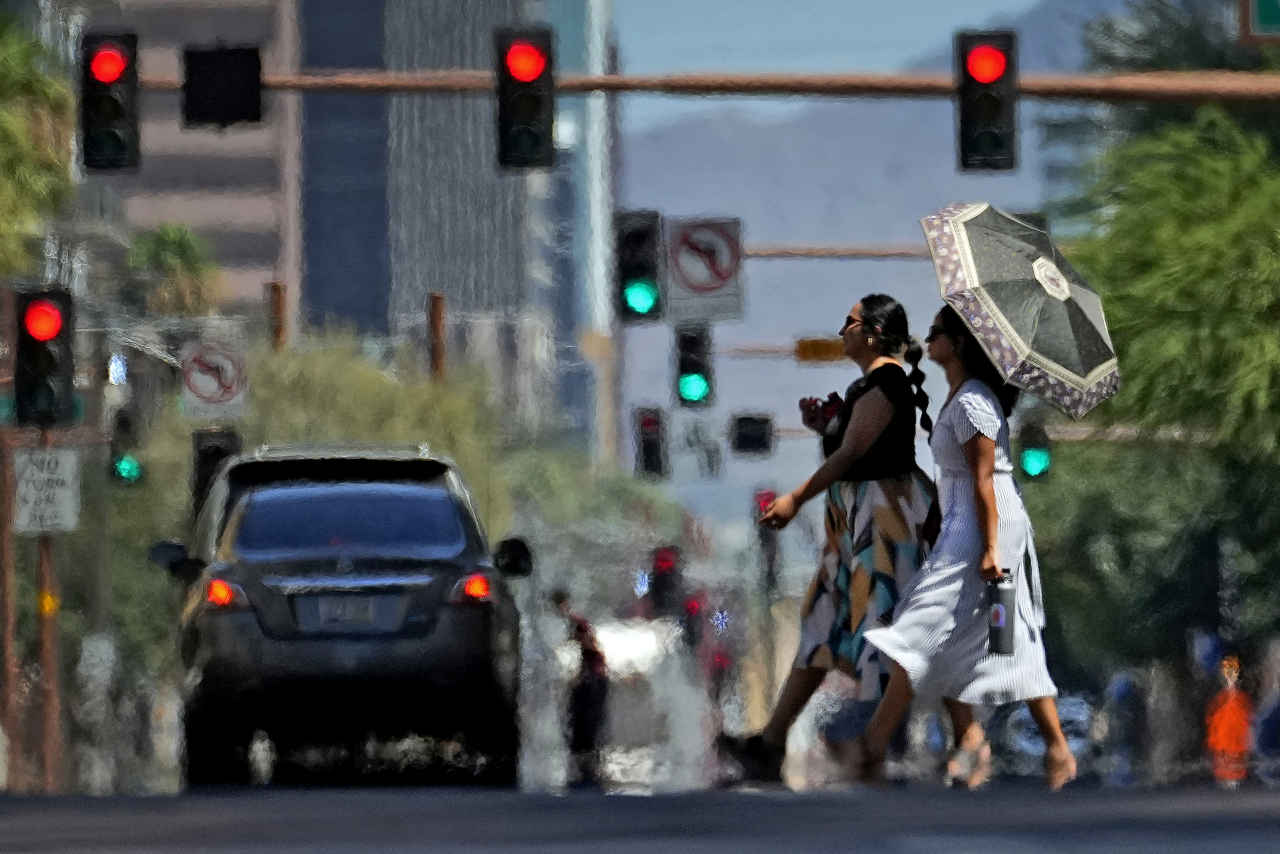 In this file photo, heat ripples engulf two ladies while crossing the street in downtown Phoenix, the US, on July 17. (AP)