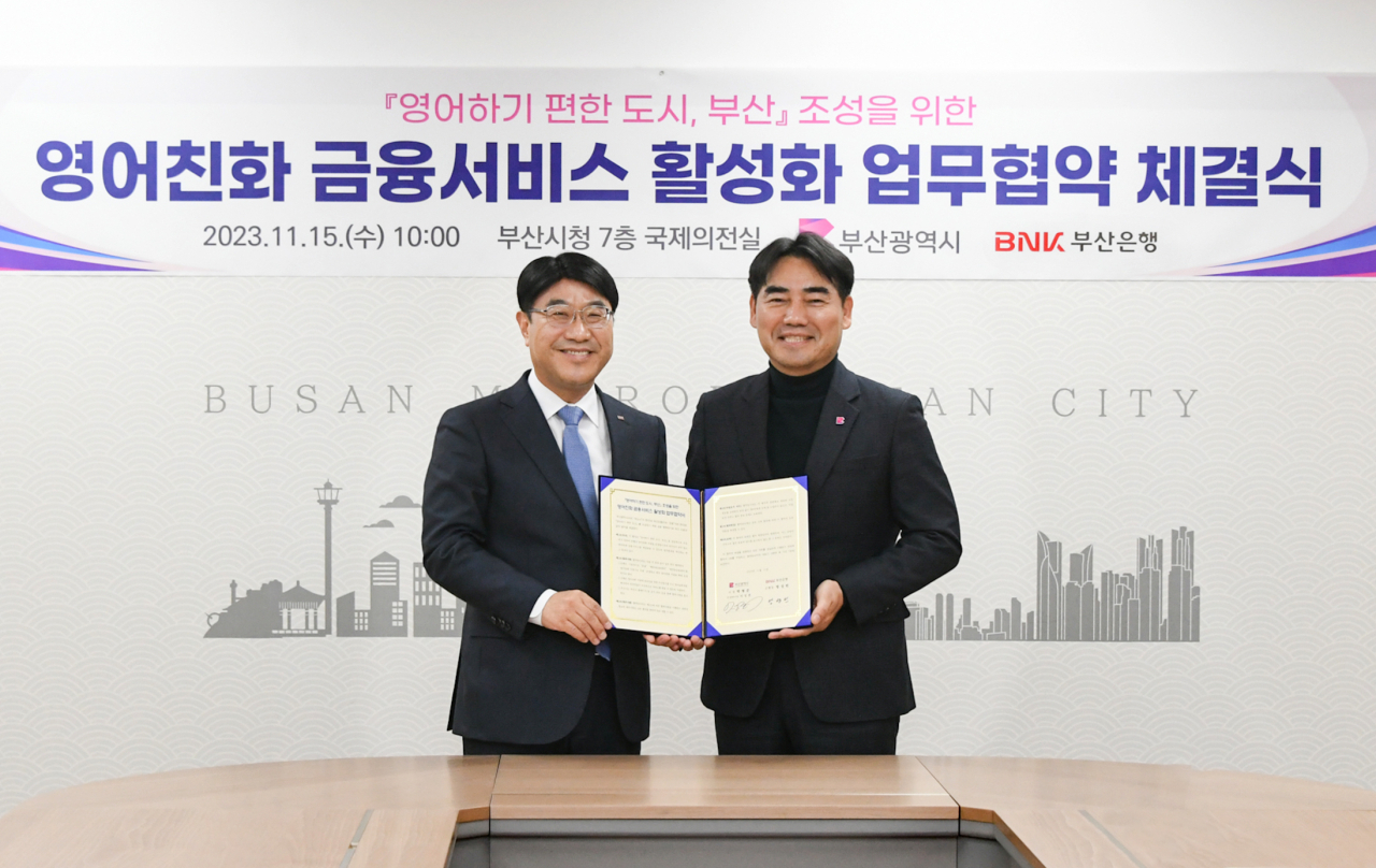 BNK Busan Bank CEO Bang Seong-bin (left) and Busan Vice Mayor for Economic Affairs Lee Seong-kweun pose for a photo after signing a memorandum of understanding to jointly provide English-speaking financial services on Wednesday at the Busan Metropolitan City Hall. (BNK Busan Bank)