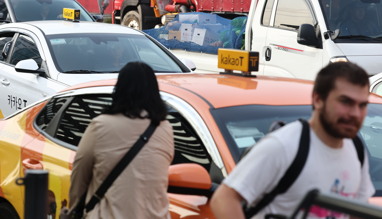 People take taxis using Kakao Mobility's ride-hailing service in Seoul. (Yonhap)