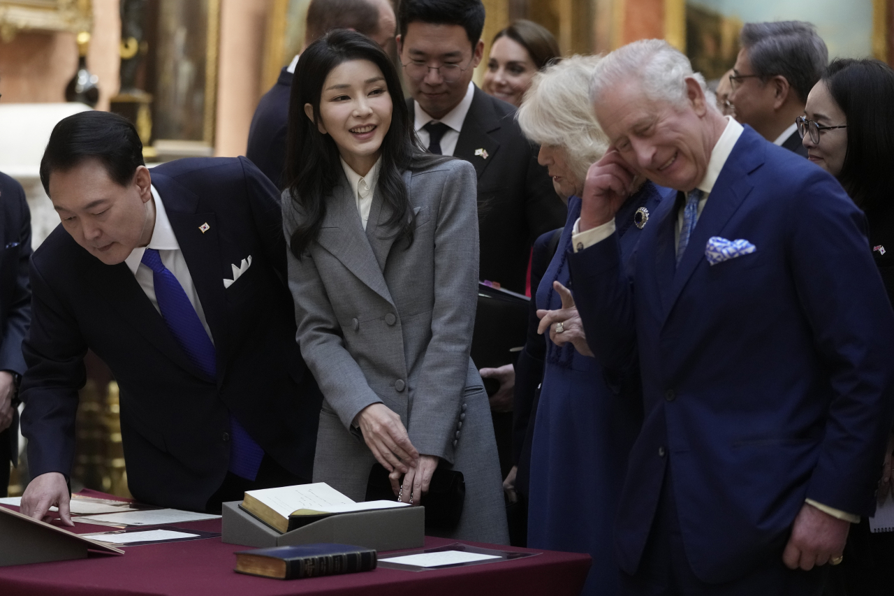 The UK's King Charles III, right, with Queen Camilla, shows The President of Korea Yoon Suk Yeol, left and First Lady, Kim Keon Hee, second left, a display of Korean items from the Royal Collection, inside Buckingham Palace in London Tuesday. (AP-Yonhap)