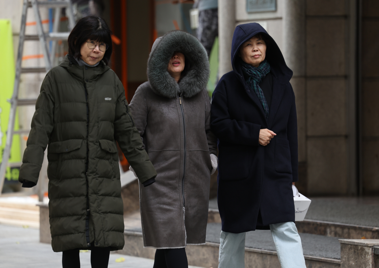People walk in heavy winter clothes in Seoul on Friday as morning temperatures drop to below 0 degrees Celcius. (Yonhap)