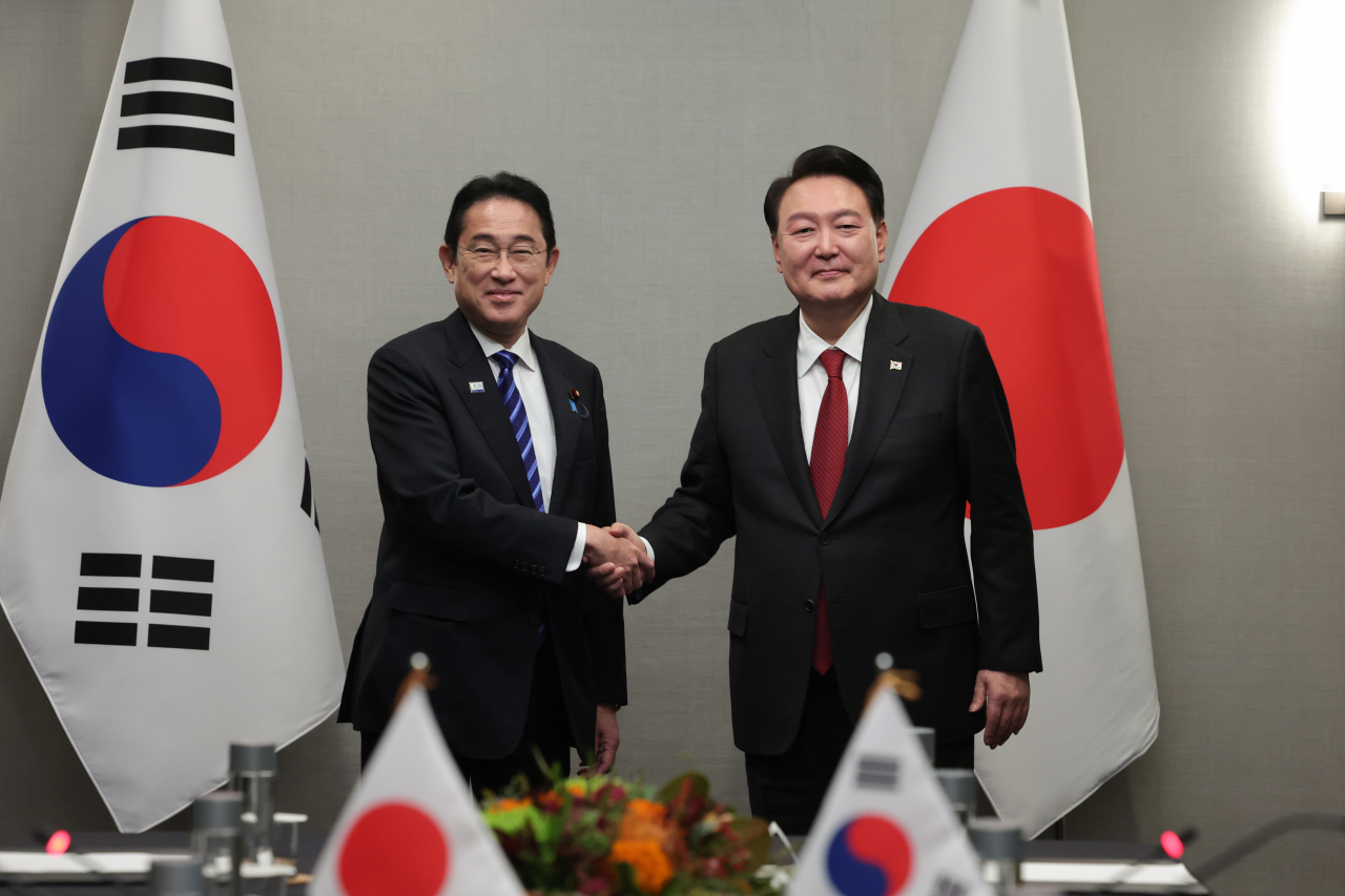 South Korean President Yoon Suk Yeol (right) and Japanese Prime Minister Fumio Kishida shake hands during their summit at a hotel in San Francisco on Nov. 16. (Yonhap)