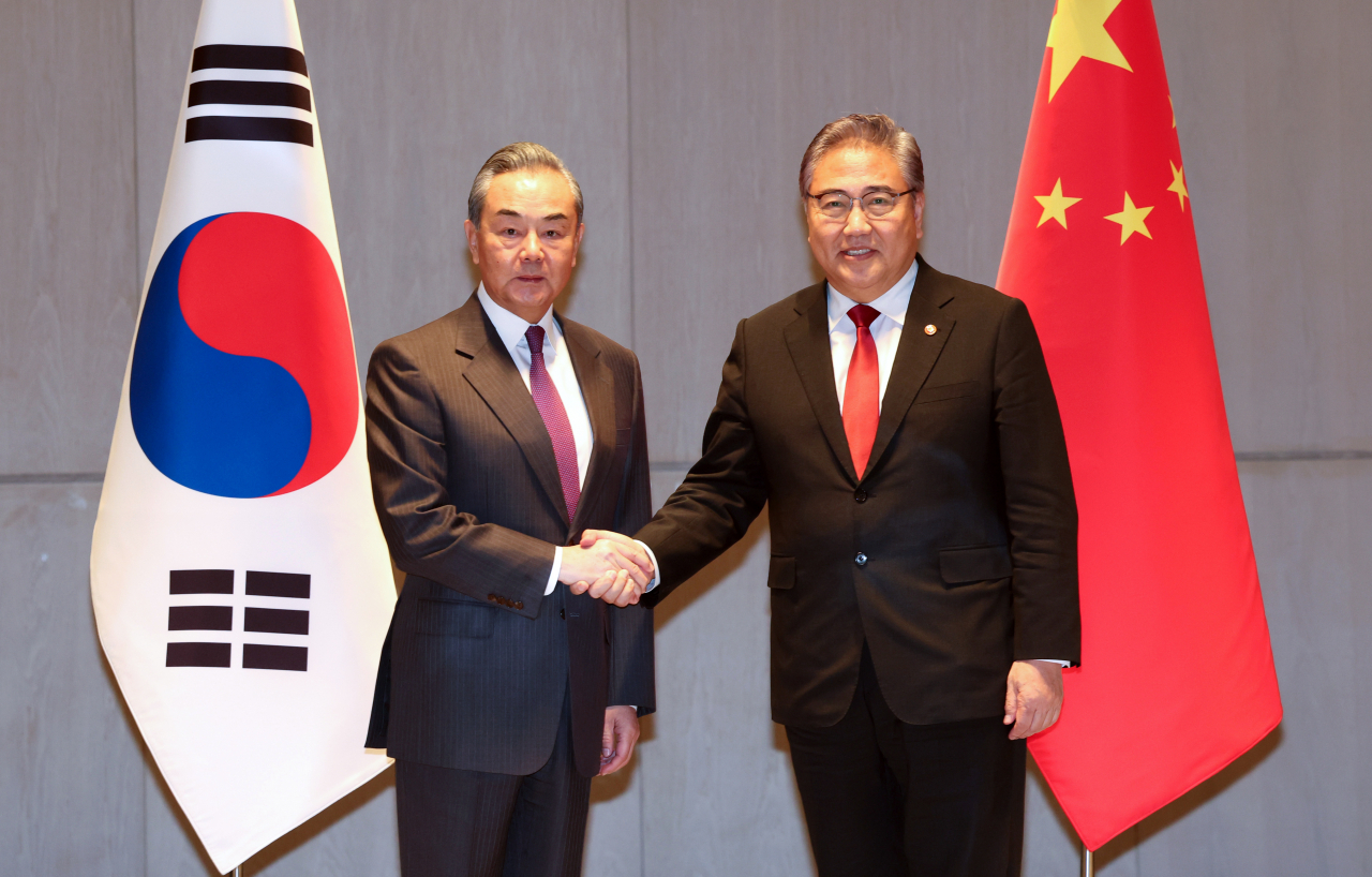 Foreign Minister Park Jin (right) shakes hands with Chinese Foreign Minister Wang Yi ahead of their bilateral talks in Busan on Sunday, the venue for a trilateral gathering with their Japanese counterpart, Yoko Kamikawa. (Yonhap)