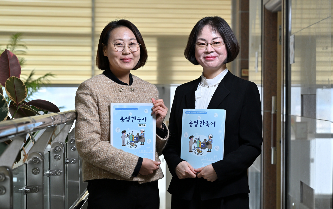 Professors Son Hye-jin (left) and Lee Mi-sun pose for the camera while holding books titled 