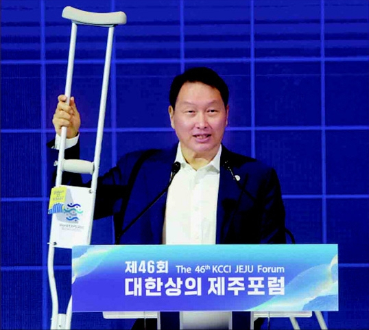 SK Chairman Chey Tae-won raises his crutch decorated with a promotional image for Busan’s Expo bid as he speaks at a business forum on Jeju Island on July 12. (Yonhap)