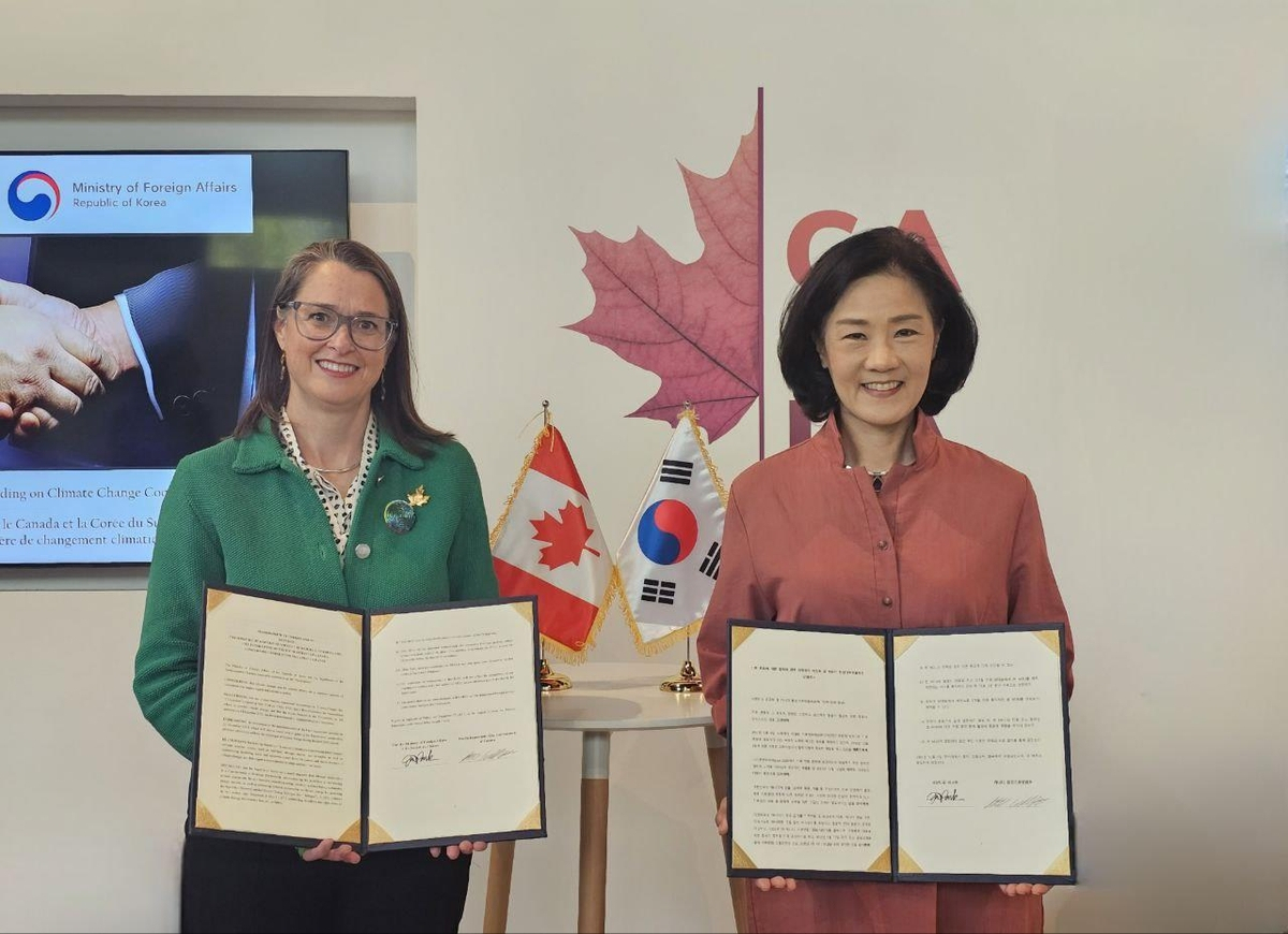 Kim Hyo-eun (right), South Korea's ambassador and deputy minister for climate change, poses for a photo with Canadian Ambassador for Climate Change Catherine Stewart, after signing a memorandum of understanding on climate change cooperation, on the margins of the 2023 UN Climate Change Conference in Dubai on Sunday. (Yonhap)