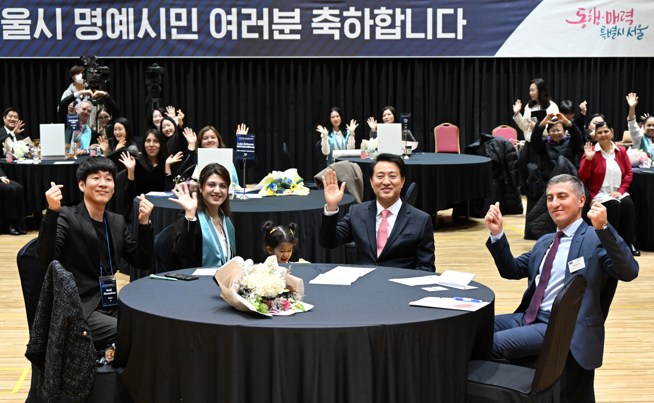 Seoul Mayor Oh Se-hoon (second from right) waves to the camera with the recipients of the certificate of honorary citizenship at Seoul City Hall on Friday. (Seoul Metropolitan Government)