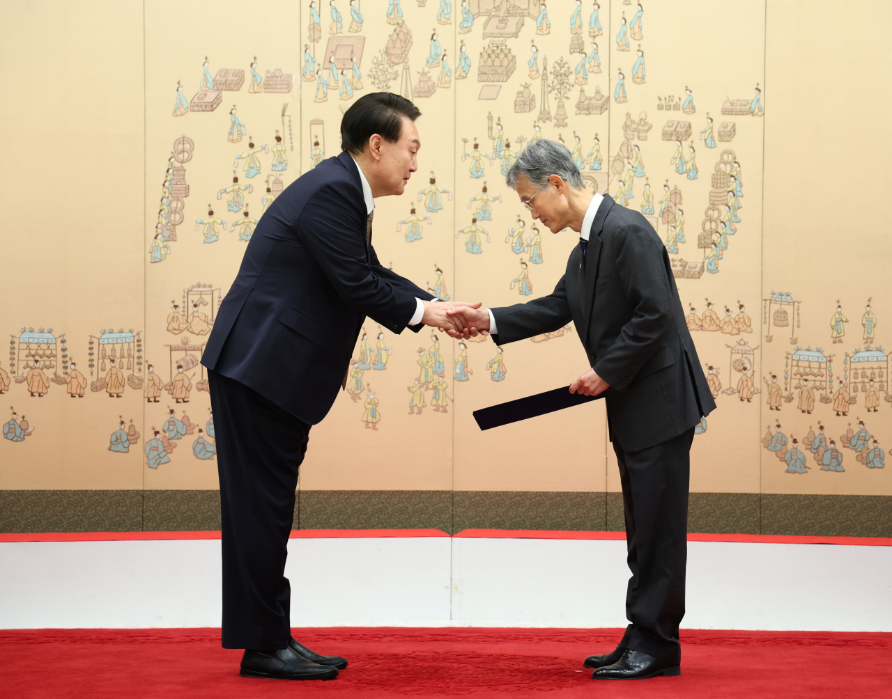 President Yoon Suk Yeol (left) shakes hands with Chief Justice nominee Cho Hee-dae at the celebration of Cho's confirmation at the presidential office on Friday. (Yonhap)