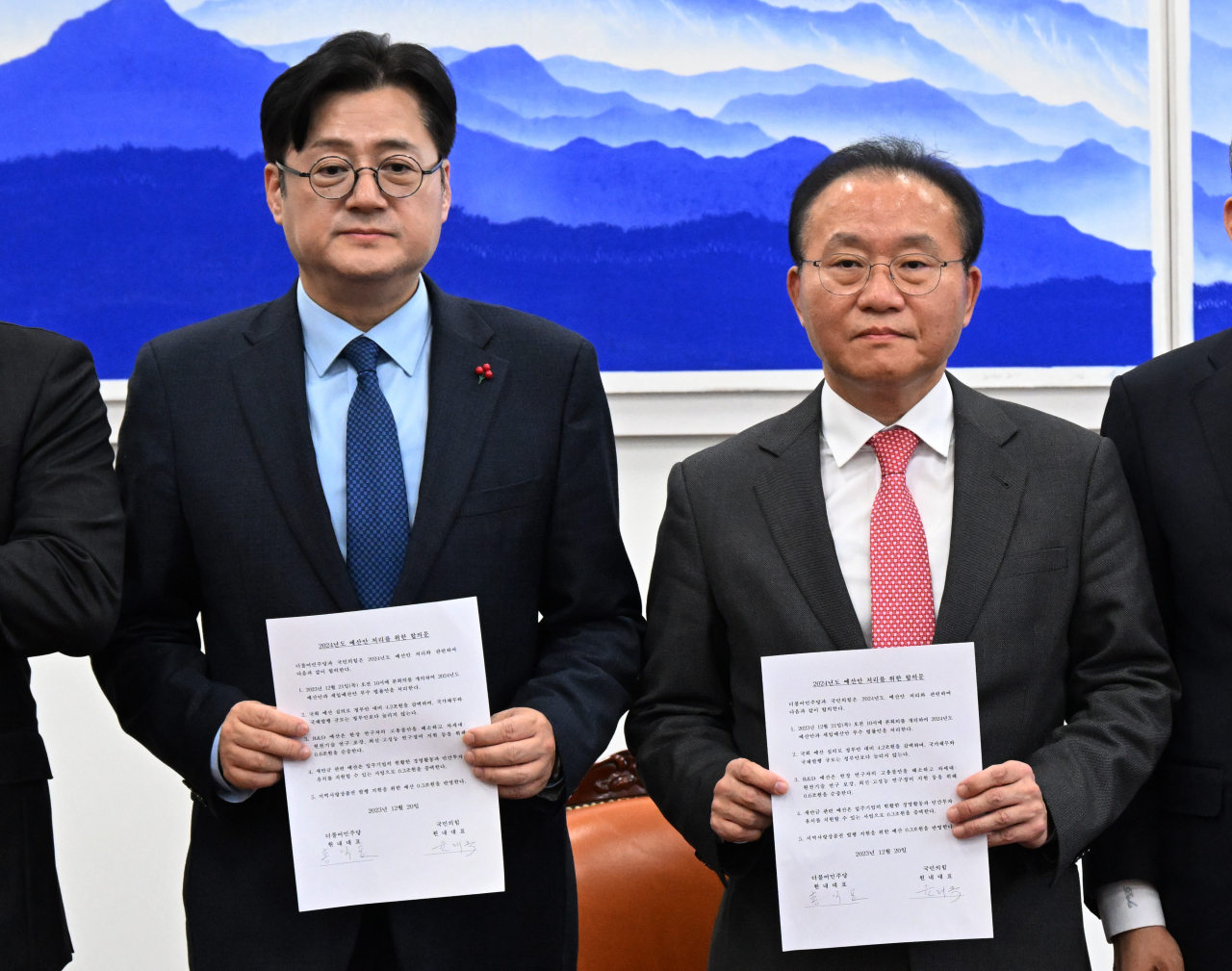 Yun Jae-ok, floor leader of the ruling People Power Party, and Hong Ik-pyo, floor leader of the main opposition Democratic Party of Korea, pose for a photo at the National Assembly in Seoul on Wednesday afternoon after reaching a final agreement on the 2024 budget. (Yonhap)