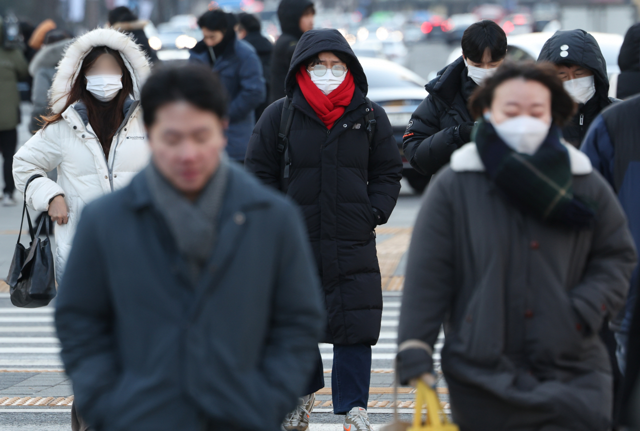 Pedestrians dressed in winter gear walk in Gwanghwamun Square on Thursday morning. (Yonhap)