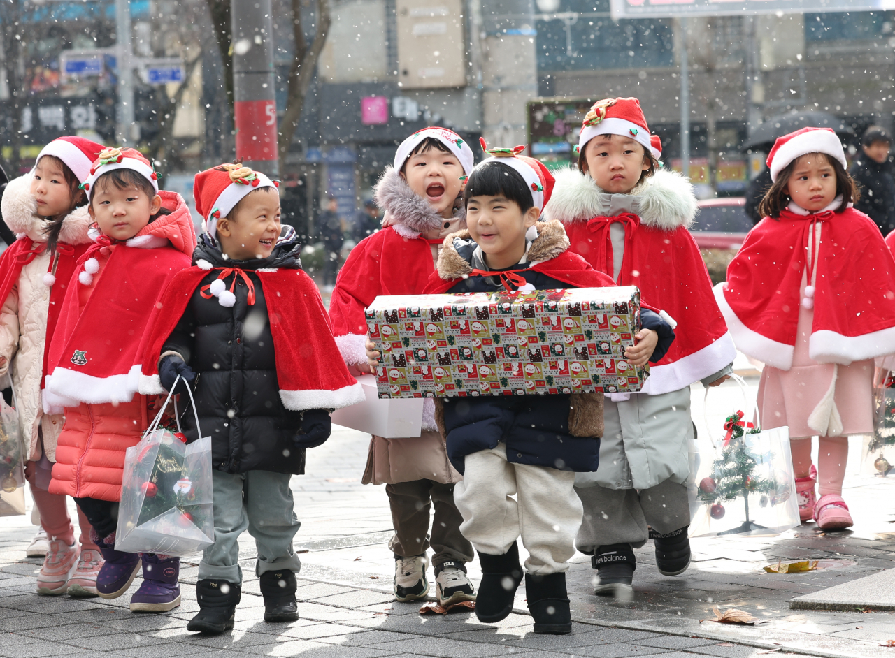 Children from a daycare center in Gwangju city dressed as Santas deliver donations along with trees and presents they made for those in need on Wednesday. (Yonhap)