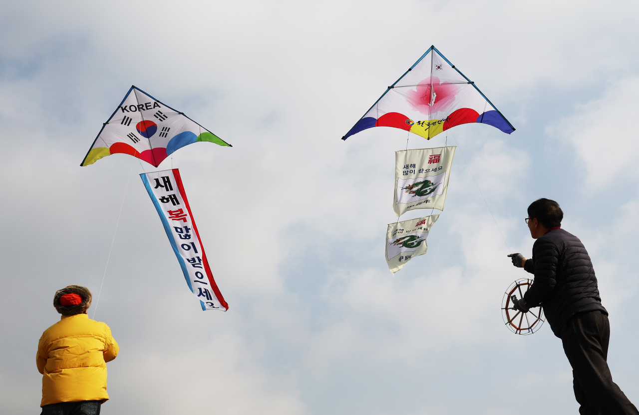 People fly kites with New Year's greetings and drawings of 2024's blue dragon to commemorate the upcoming New Year at Changryongmun of Suwon Hwaseong Fortress on Thursday. (Yonhap)