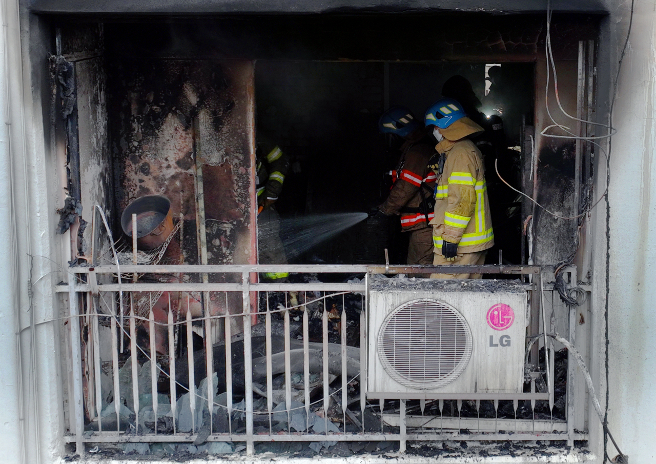 Firefighters douse the remains of a fire at a 15-story apartment in Gunpo, Gyeonggi Province, Tuesday. (Yonhap)