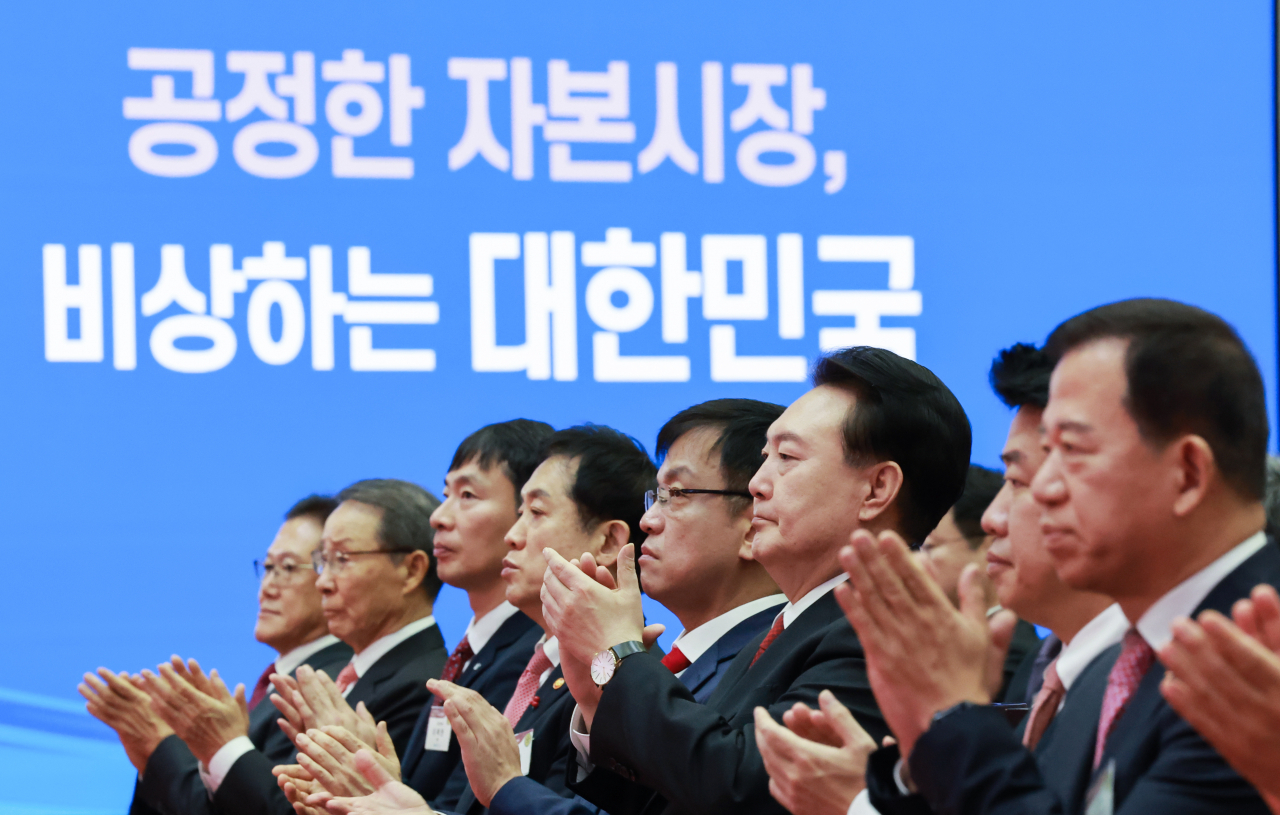 President Yoon Suk Yeol (sixth from left) claps hands with participants at the market open ceremony at the Korea Exchange, South Korea's sole stock market operator, in Seoul on Tuesday, (Yonhap)