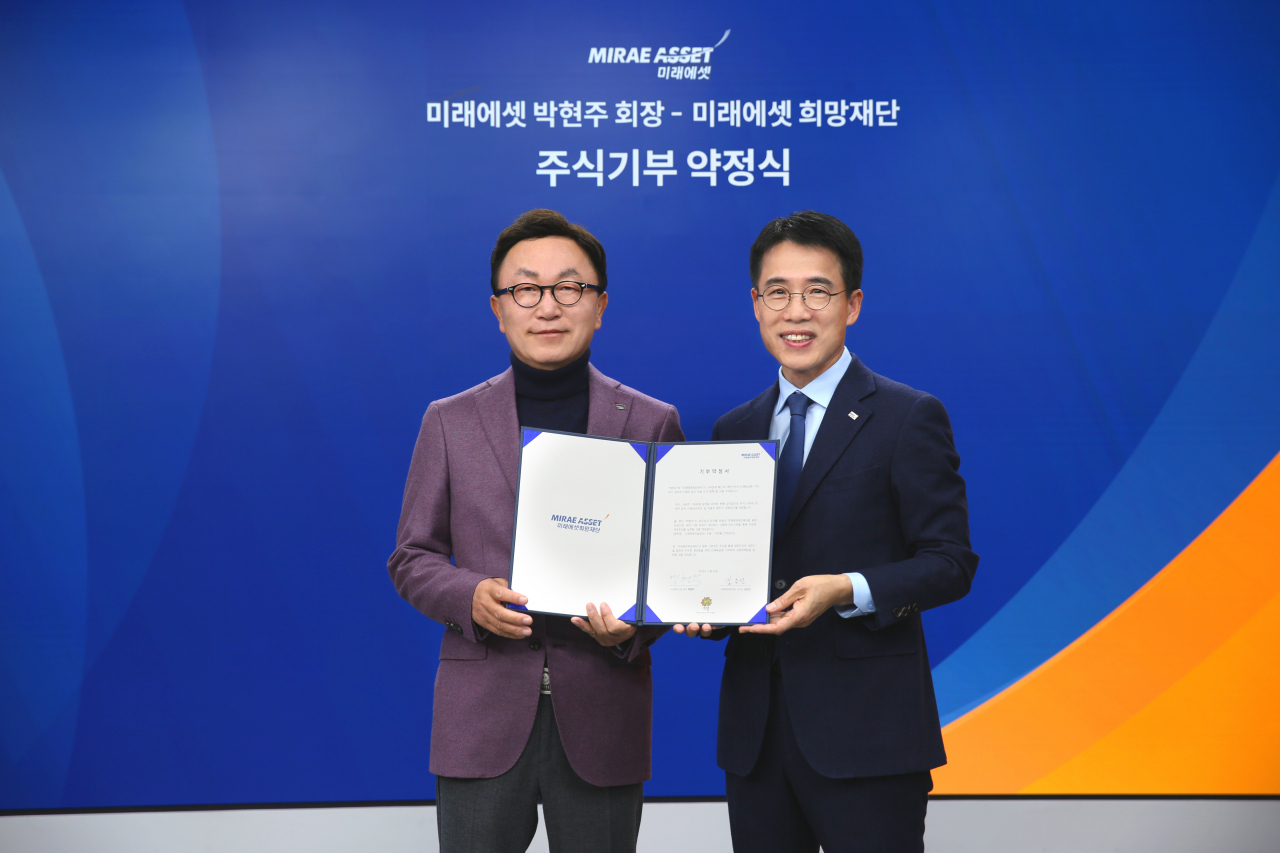Mirae Asset Financial Group Chairman Park Hyeon-joo (left) poses for a photo after pledging to donate 25 percent of his stake in Mirae Asset Consulting to the Mirae Asset Hope Foundation at the Mirae Asset Center One in central Seoul, Dec. 26. (Mirae Asset Global Investments)