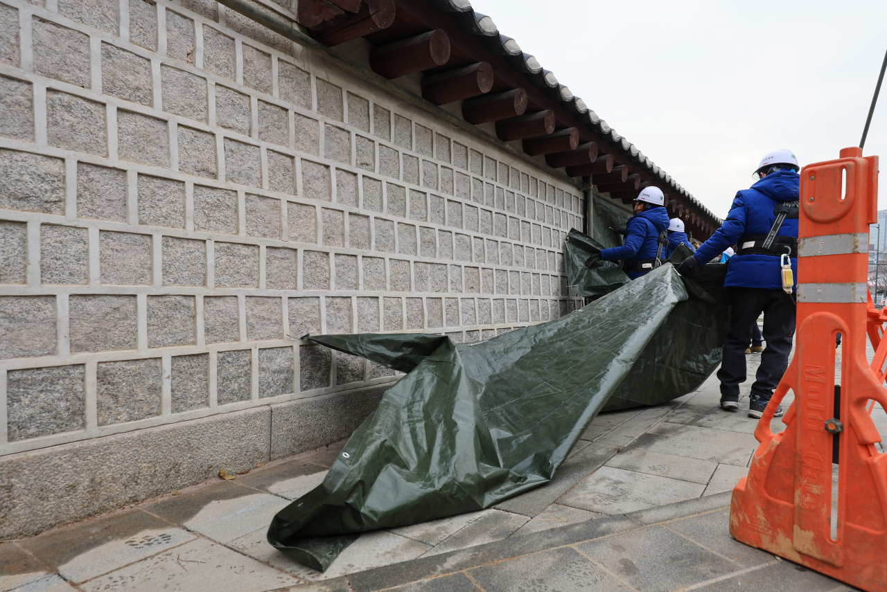 Workers remove a tarp covering the vandalized part of the Gyeongbokgung wall on Jan. 4. (Yonhap)