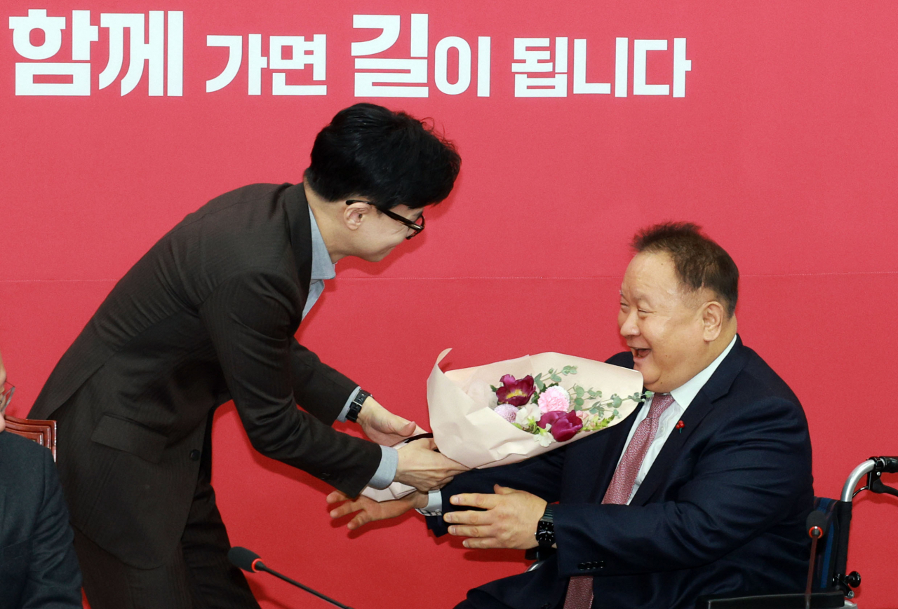 People Power Party interim Chairman Han Dong-hoon (left) welcomes five-term lawmaker and ex-Democratic Party Rep. Lee Sang-min with a bouquet of flowers, as Lee officially announced that he was joining the ruling party at the National Assembly on Monday. (Yonhap)