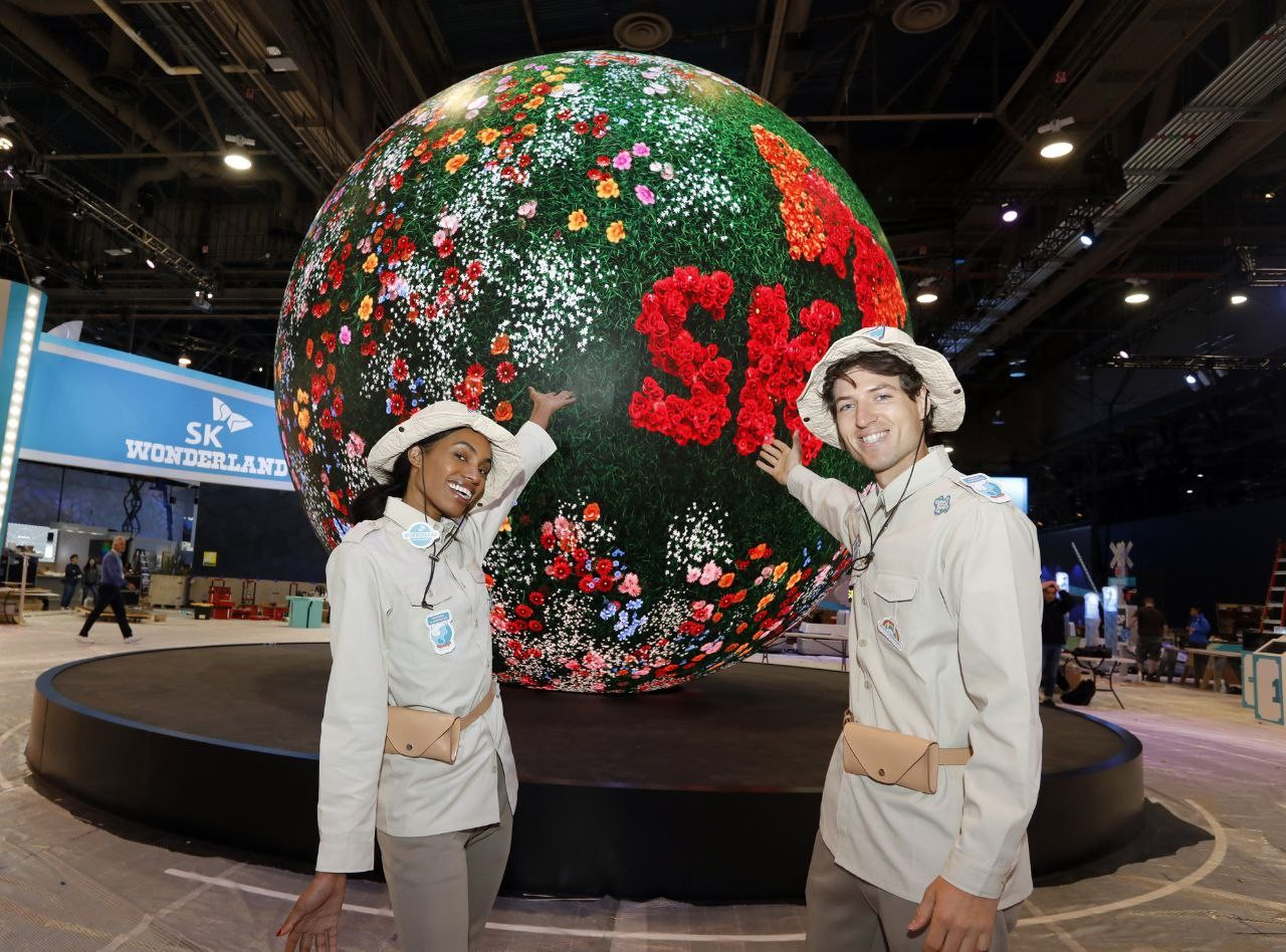 Employees pose in front of a spherical LED screen, dubbed 