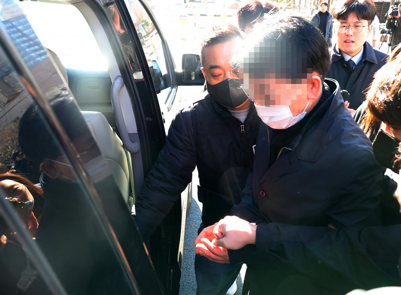 The suspect in the stabbing of Democratic Party of Korea leader Lee Jae-myung is escorted by police after attending a review of his arrest warrant at the Busan District Court on Thursday. (Yonhap)