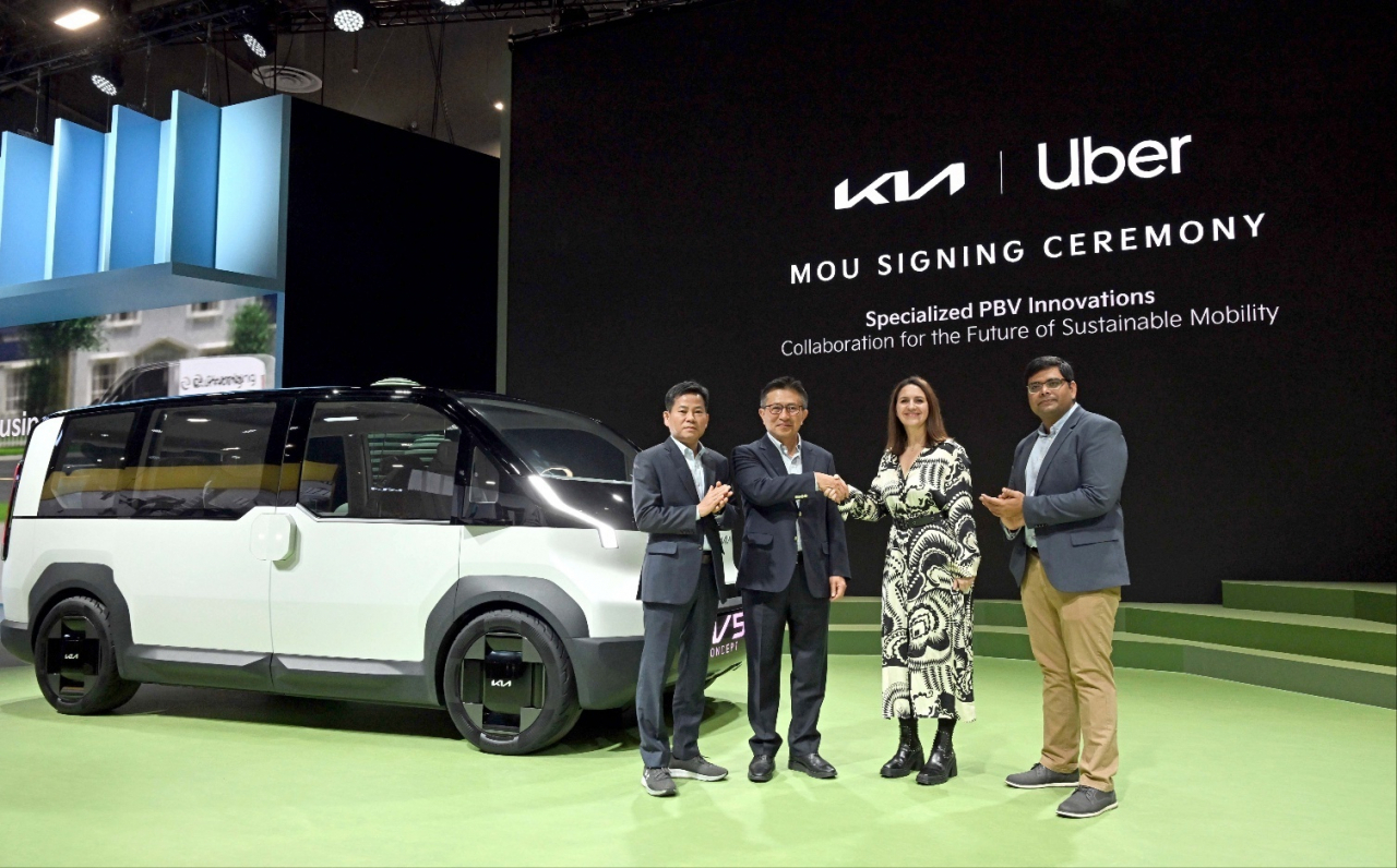 Kia and Uber officials pose for a photo as they announce their partnership agreement to develop electric purpose-built vehicles for Uber's ride-hailing services at the CES 2024 in Las Vegas on Wednesday. (Hyundai Motor Group)