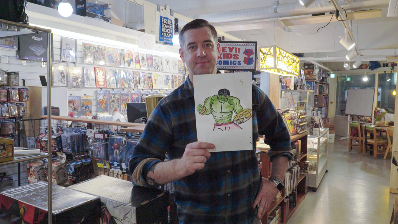 Croner holds up his drawing of the Hulk holding the cafe's signature cheeseburgers. The week's 