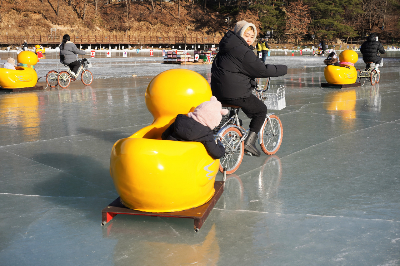 A mother takes her daughter on a tricycle sled ride at Sanjeong Lake on Monday. (Lee Si-jin/The Korea Herald)