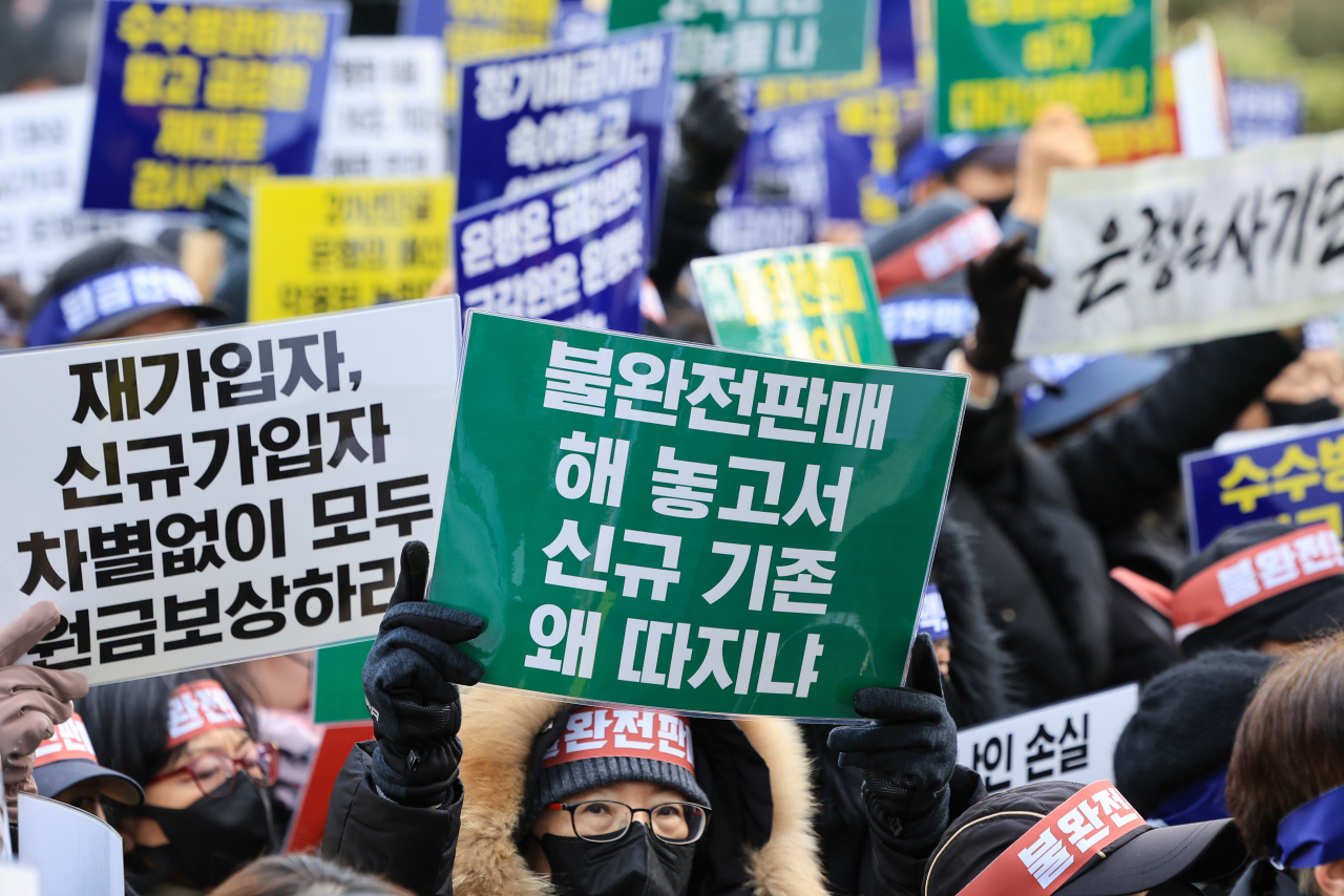 Retail investors of equity-linked securities products underlying Hong Kong's slumping Hang Seng China Enterprises Index hold up signs demanding equal compensation for first-time investors and re-purchasers during a rally held in front of the Financial Supervisory Service building in Yeouido, Seoul, Friday. (Yonhap)