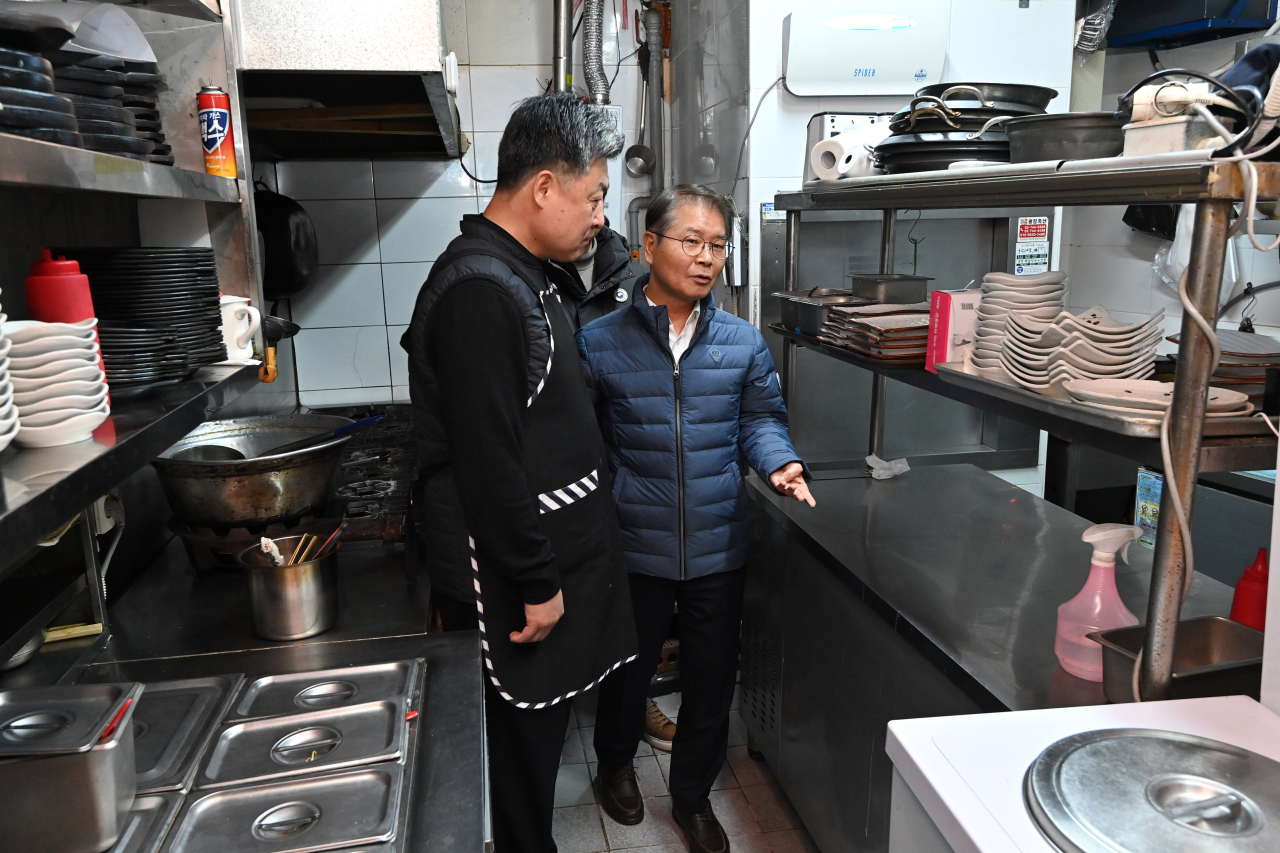 Labor Minister Lee Jeong-sik (right) inspects a kitchen at a restaurant in Seoul on Monday, two days after expanded implementation of the Serious Accidents Punishment Act, a workplace safety law aimed at penalizing employers for serious industrial accidents, went into force as scheduled. (Yonhap)
