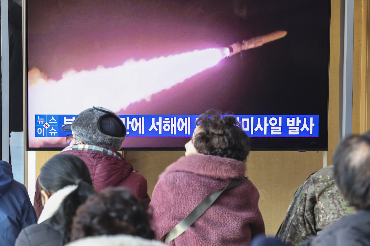 People watch a TV news report on North Korean cruise missile launch at a Seoul station on Wednesday. (Yonhap)