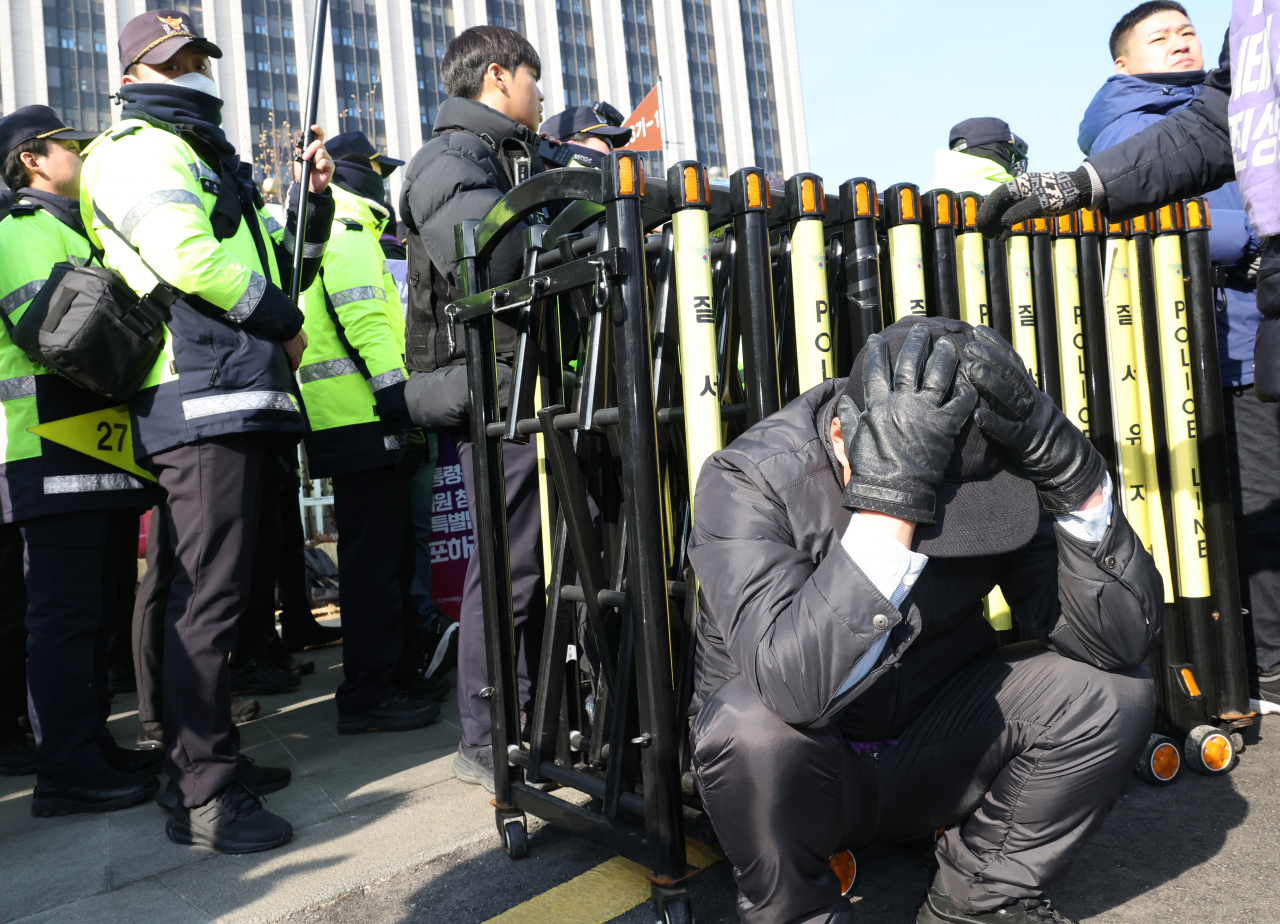 A man crouches while covering his head with both hands in front of the Government Complex Seoul on Tuesday. (Yonhap)