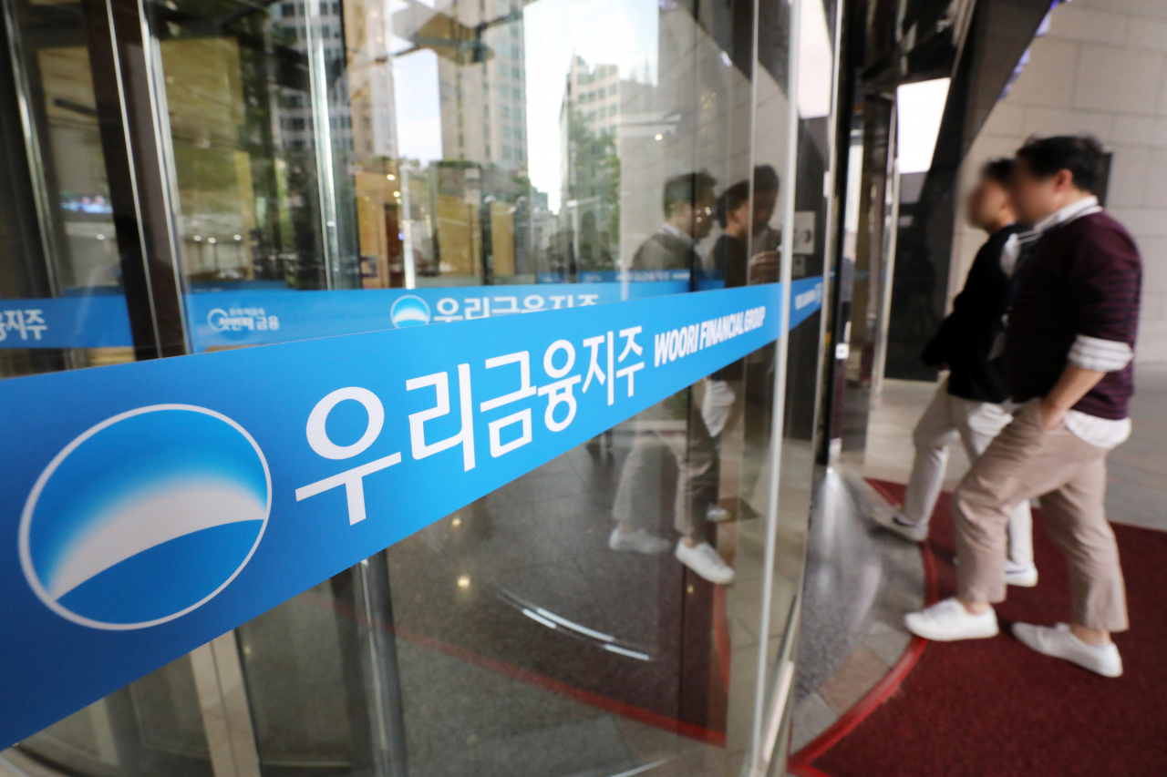 People walk into a building with a sign showing the name of Woori Financial Group at the conglomerate's building in Seoul in 2023. (Newsis)