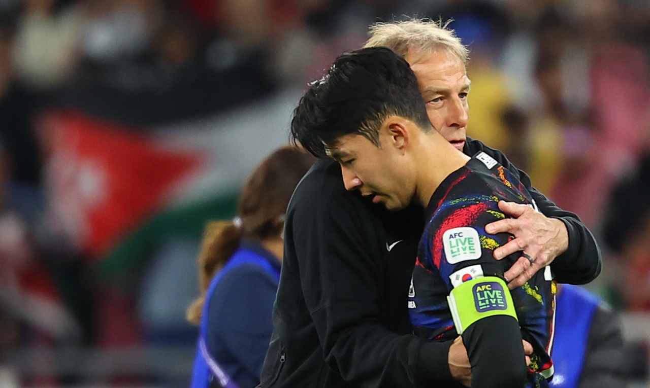 Son Heung-min (right), the captain of the South Korean men's national soccer team, embraces his coach Juergen Klinsmann after the 2-0 loss to Jordan in the semifinals match of the AFC Asian Cup in Qatar on Tuesday at the Ahamd bin Ali Stadium in Al Rayyan. (Yonhap)