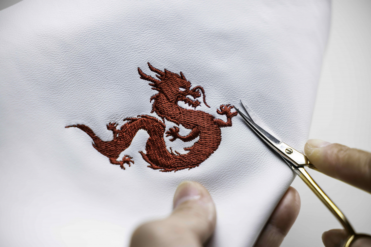 A Rolls-Royce craftsman trims the edges of the Phonix Red embroidery. (Rolls-Royce Motor Cars)