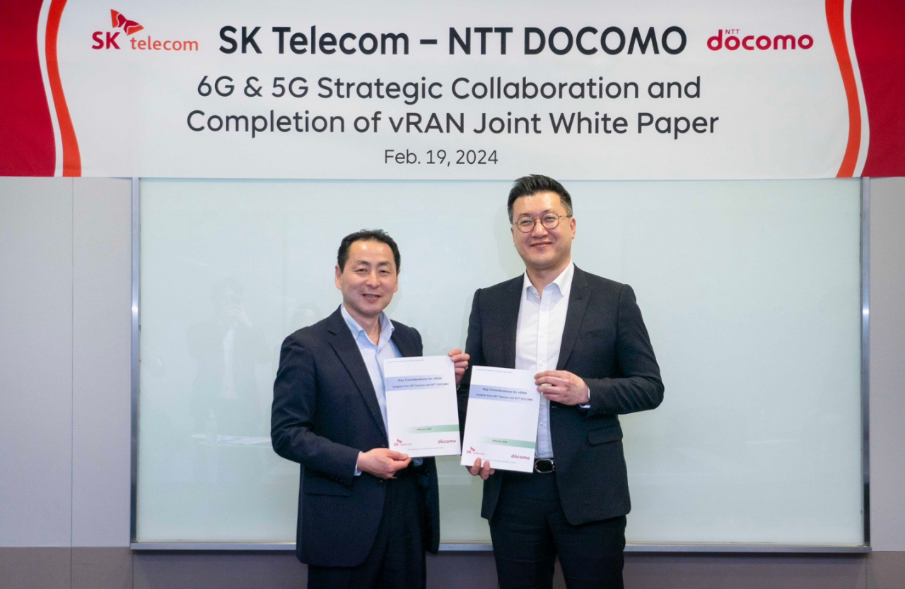 Takehiro Nakamura (left), chief standardization officer of NTT Docomo, and Yu Tak-ki, vice president and head of the Infra Tech Office of SKT, pose for a photo with the newly released vRAN joint white paper on Monday at the SKT headquarters in Seoul. (SK Telecom)