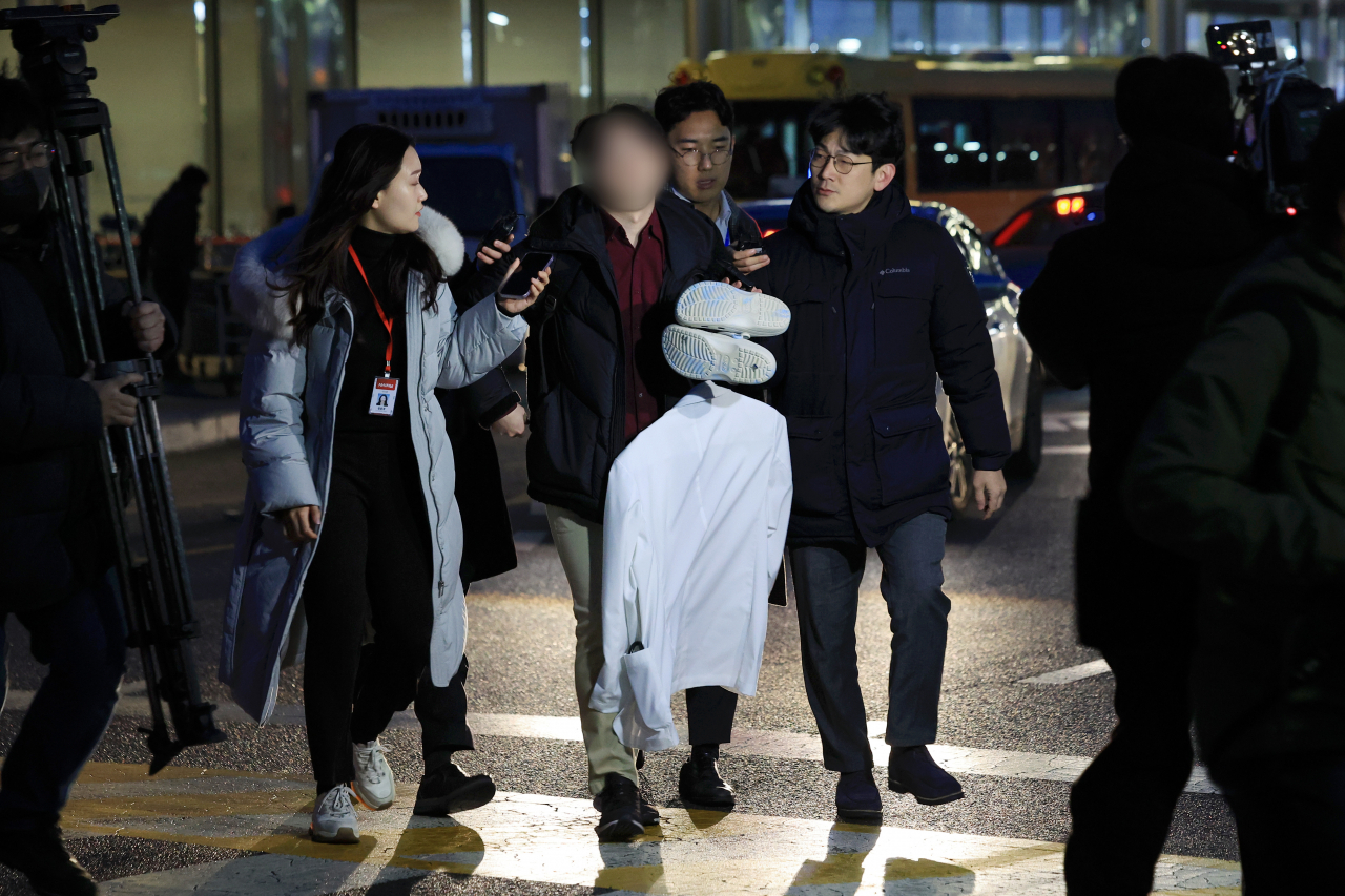 A doctor leaves the hospital holding a white coat, Tuesday morning. (Yonhap)