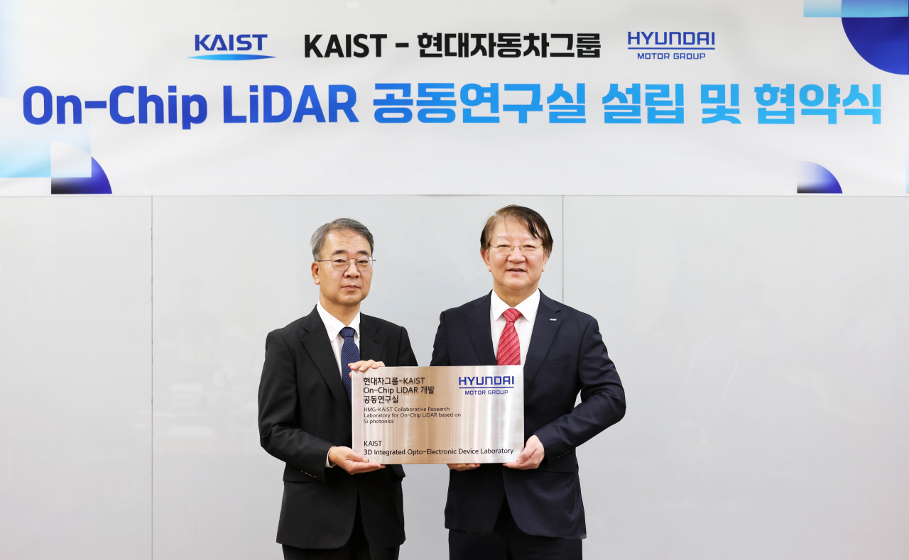 Lee Jong-soo (left), executive vice president at Hyundai Motor, and Lee Sang-yup, senior vice president for research at KAIST, pose for a photograph as they hold a signboard commemorating the establishment of their joint laboratory to develop on-chip lidar at the KAIST campus in Daejeon on Monday. (Hyundai Motor Group)