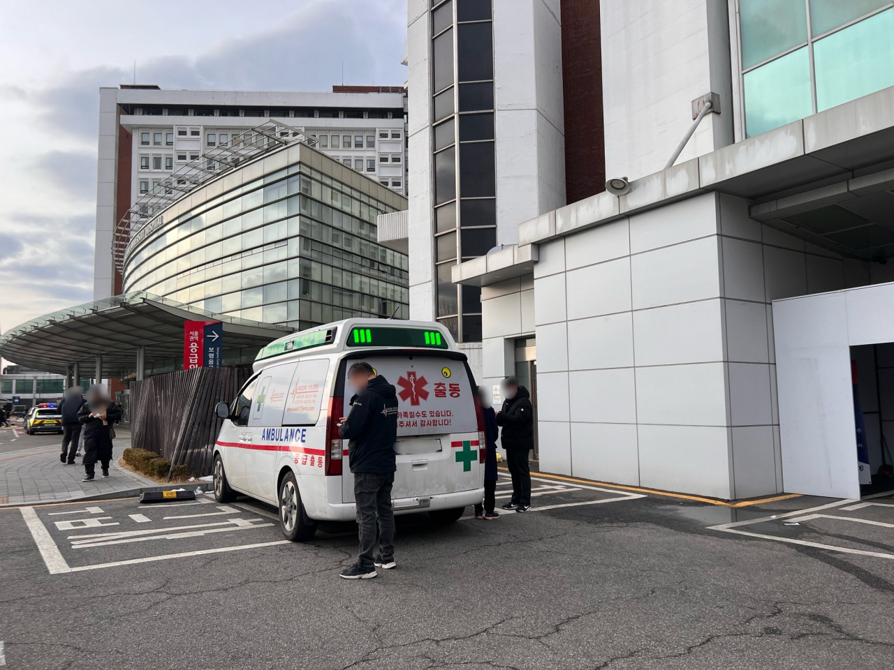 A woman and 119 paramedics wait in front of the ambulance at Seoul National University Hospital in Jongno-gu, central Seoul, Friday. (Park Jun-hee/The Korea Herald)