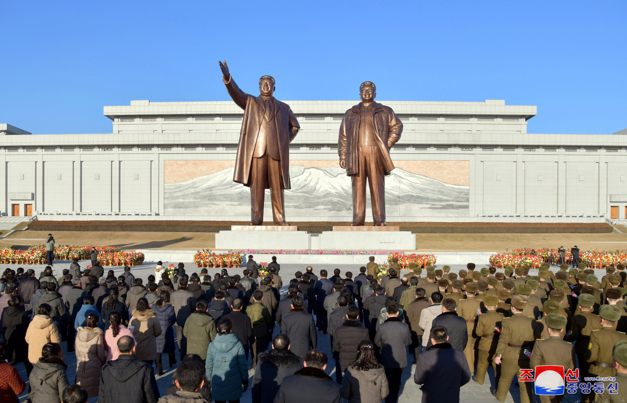 North Koreans pay respect to the statues of former late leaders Kim Il-sung and Kim Jong-il in Pyongyang on Feb. 16 in this photo carried by the Korean Central News Agency the next day. The event came on the occasion of the 82nd birthday of the North's former late leader Kim Jong-il. (Yonhap)